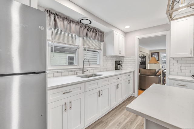 592 Courtland Ave, Bridgeport, CT 06605 - kitchen featuring freestanding refrigerator, a sink, decorative backsplash, light wood-style flooring, and white cabinetry