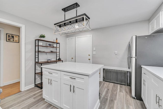 592 Courtland Ave, Bridgeport, CT 06605 - kitchen with freestanding refrigerator, light wood-type flooring, radiator, white cabinets, and light countertops