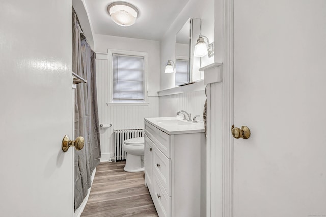 592 Courtland Ave, Bridgeport, CT 06605 - bathroom featuring radiator, toilet, vanity, a wainscoted wall, and wood finished floors