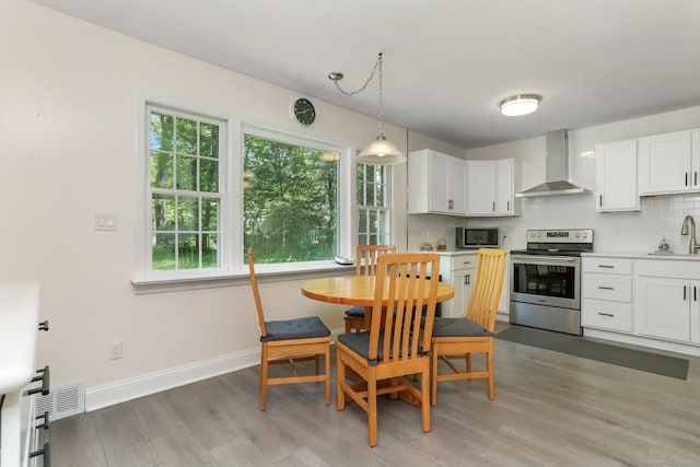 24 Richards Ln, Norwalk, CT 06851 - kitchen with stainless steel appliances, wall chimney range hood, a sink, light wood-style floors, and decorative backsplash