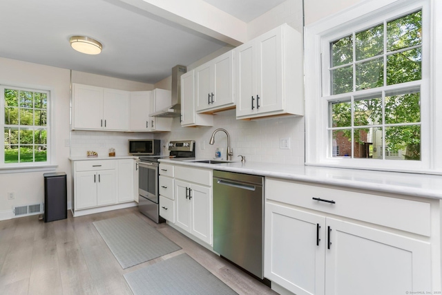 24 Richards Ln, Norwalk, CT 06851 - kitchen with stainless steel appliances, wall chimney exhaust hood, a sink, backsplash, and light countertops