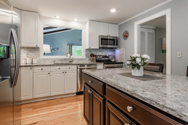 121 Dinatali Dr, Waterbury, CT 06705 - kitchen with stainless steel appliances, a sink, white cabinets, backsplash, and light wood finished floors