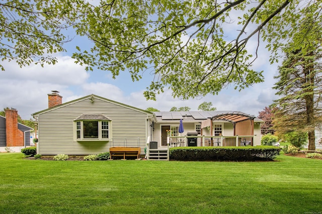 121 Dinatali Dr, Waterbury, CT 06705 - rear view of house with a yard, a deck, roof mounted solar panels, and a chimney
