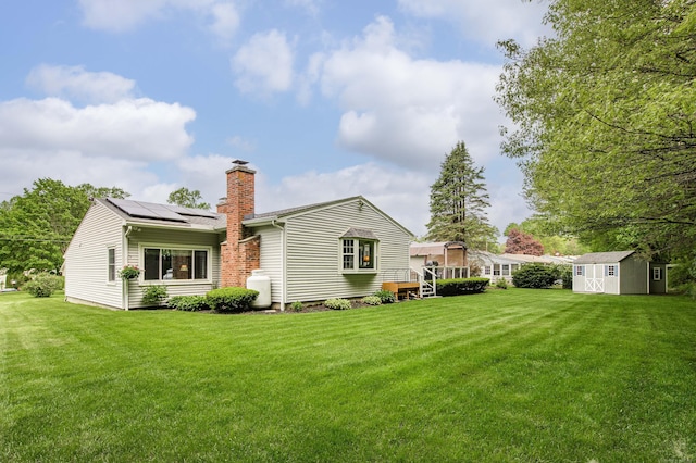 121 Dinatali Dr, Waterbury, CT 06705 - back of property with a chimney, a storage unit, solar panels, an outdoor structure, and a lawn