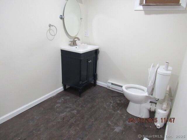 bathroom featuring baseboard heating, toilet, vanity, and baseboards