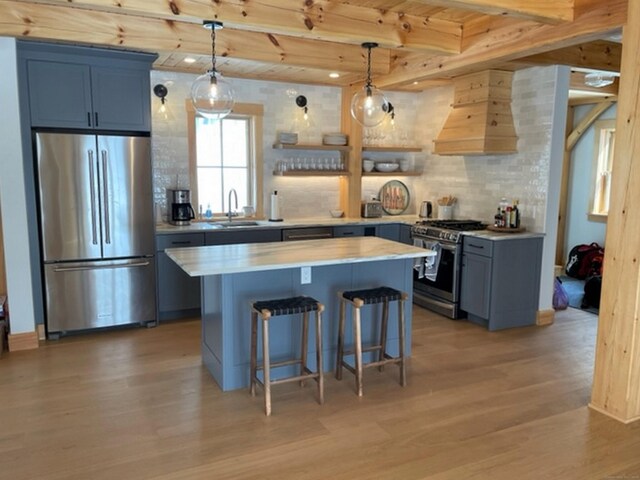 24 Calhoun St, Washington, CT 06794 - kitchen featuring stainless steel appliances, premium range hood, light wood-type flooring, a sink, and a kitchen bar