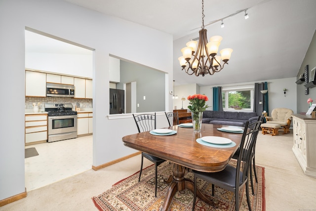 dining space featuring light carpet, a chandelier, vaulted ceiling, baseboards, and rail lighting