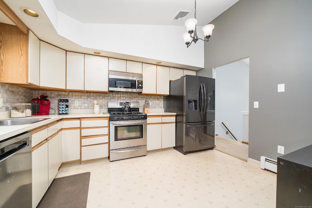 kitchen with appliances with stainless steel finishes, a sink, light countertops, a baseboard heating unit, and light floors
