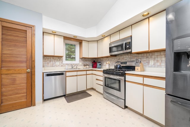 kitchen with appliances with stainless steel finishes, light countertops, decorative backsplash, light flooring, and a sink