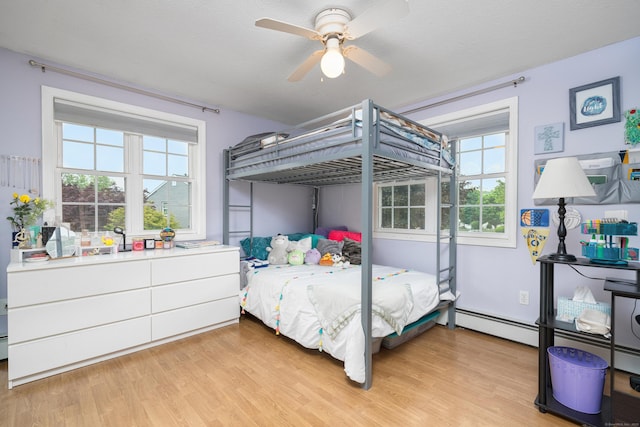 bedroom featuring a baseboard heating unit, multiple windows, light wood-type flooring, and ceiling fan