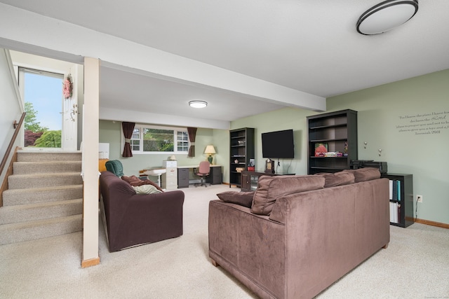 living room featuring light carpet, beamed ceiling, a desk, stairway, and baseboards