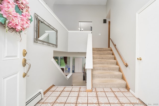 entryway with a baseboard heating unit, stairway, baseboards, and a high ceiling