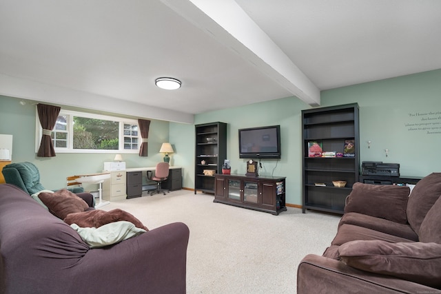 living area featuring a desk, beam ceiling, light colored carpet, and baseboards