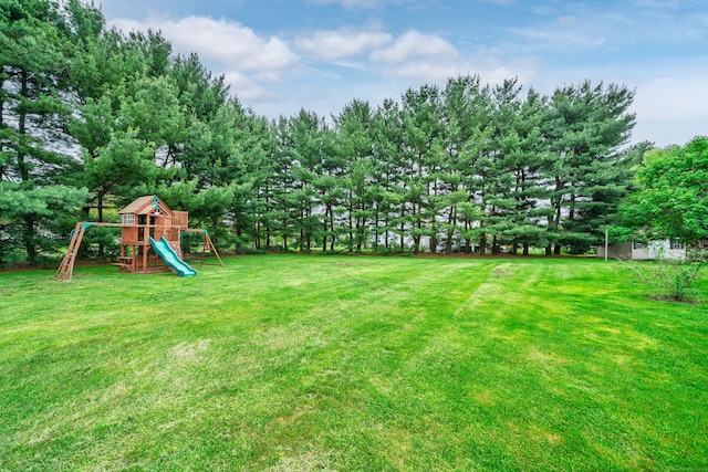 view of grassy yard with a playground and view of scattered trees