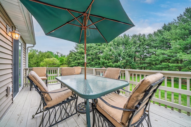 wooden deck with outdoor dining area and view of scattered trees