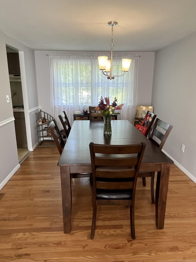 dining area with a chandelier, light wood finished floors, and baseboards