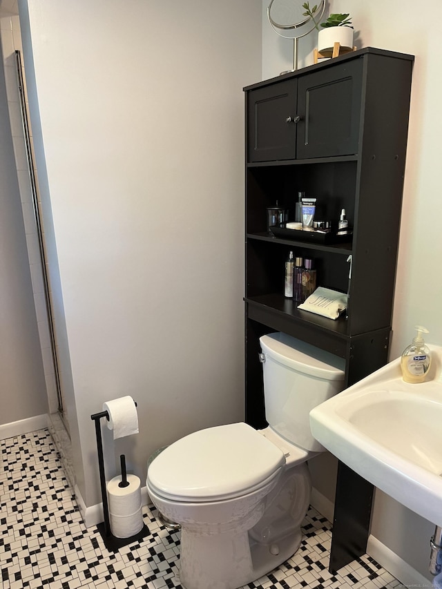 bathroom with toilet, baseboards, a sink, and tile patterned floors