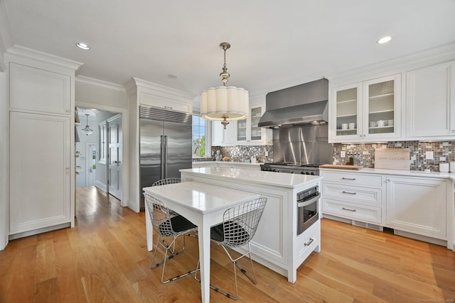 144 S Ave, New Canaan, CT 06840 - kitchen featuring wall chimney range hood, stainless steel appliances, light countertops, white cabinets, and recessed lighting