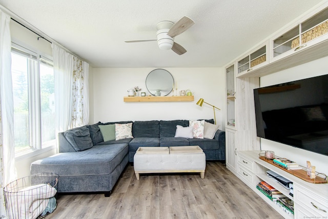 living area featuring light wood-type flooring, a ceiling fan, and a textured ceiling