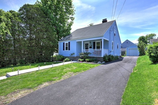 bungalow-style home featuring covered porch, an outdoor structure, a detached garage, a chimney, and a front lawn