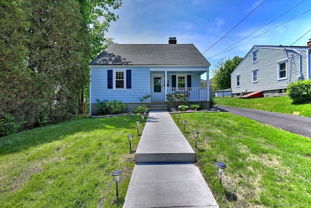 bungalow-style home featuring covered porch, a chimney, and a front yard