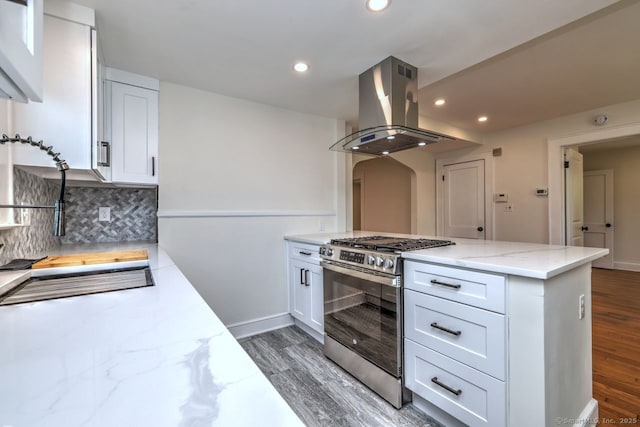kitchen with stainless steel range with gas stovetop, island range hood, light wood-style floors, decorative backsplash, and recessed lighting