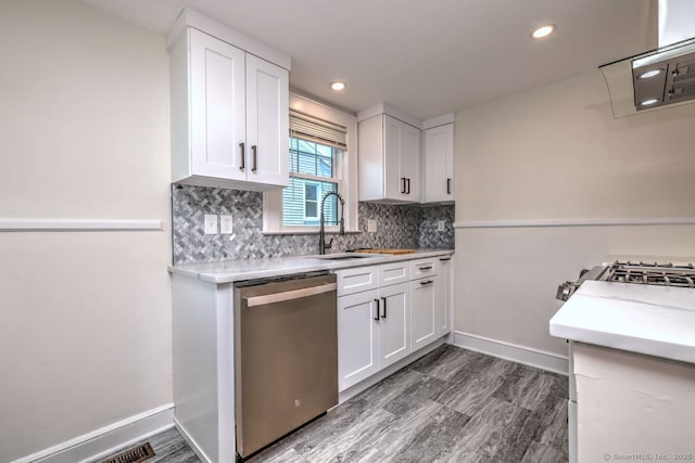 kitchen featuring dishwasher, a sink, wood finished floors, backsplash, and recessed lighting
