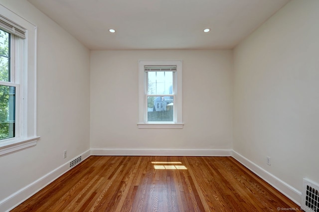 unfurnished room featuring plenty of natural light, wood finished floors, baseboards, and recessed lighting