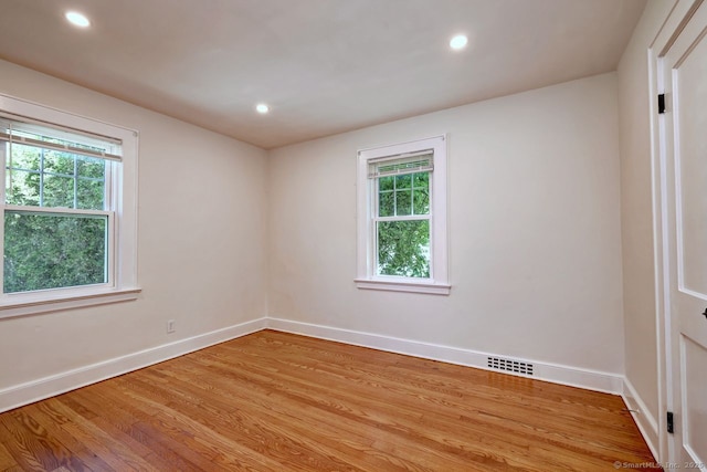 empty room with plenty of natural light, baseboards, light wood-style floors, and recessed lighting