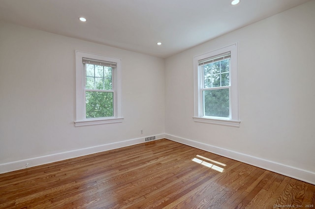 empty room with baseboards, wood finished floors, and recessed lighting