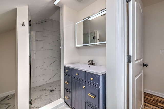 full bathroom with a shower stall, vanity, baseboards, and marble look tiles
