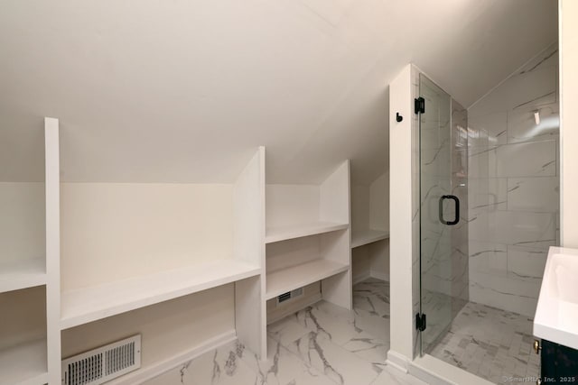 bathroom with marble look tile flooring, a marble finish shower, and lofted ceiling