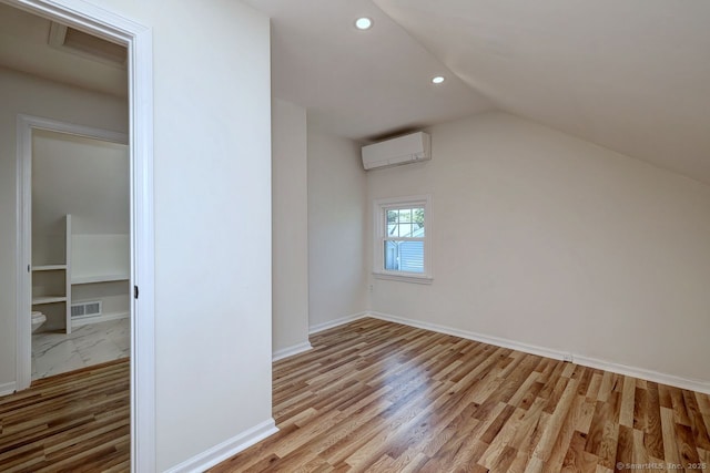 additional living space featuring an AC wall unit, recessed lighting, light wood-style floors, lofted ceiling, and baseboards