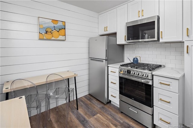 kitchen with stainless steel appliances, dark wood-type flooring, white cabinets, decorative backsplash, and light stone countertops