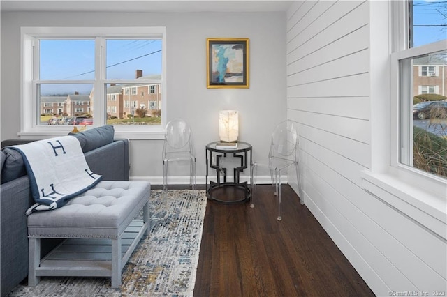 living area featuring wood finished floors, baseboards, and wooden walls
