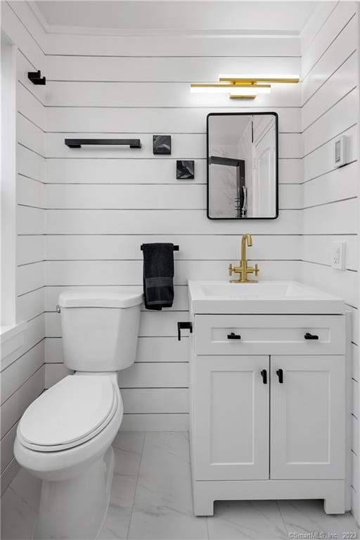 bathroom with marble finish floors, wood walls, vanity, and toilet