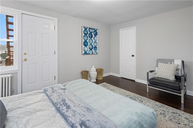 bedroom featuring wood finished floors, radiator heating unit, and baseboards