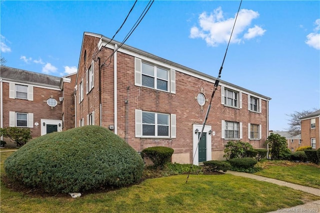 view of front facade with a front yard and brick siding