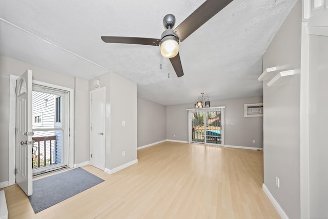 unfurnished living room with wood finished floors, ceiling fan, a chandelier, and baseboards
