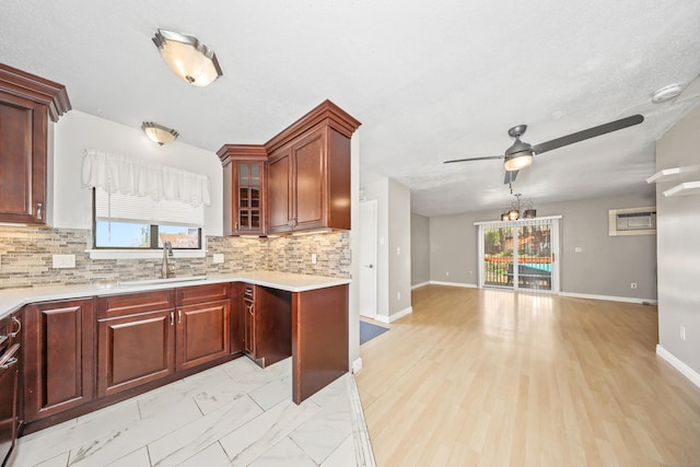 kitchen with a sink, open floor plan, light countertops, a ceiling fan, and healthy amount of natural light