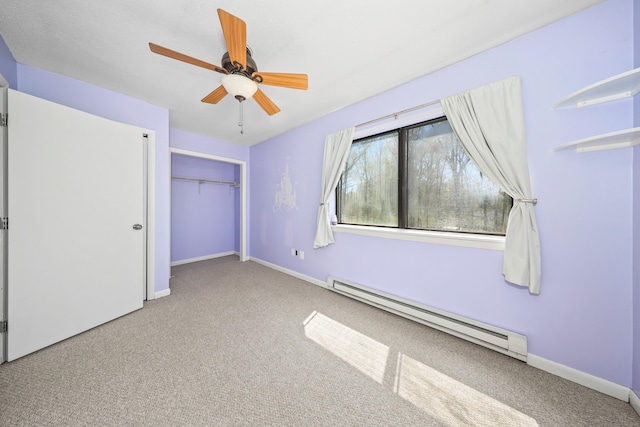 unfurnished bedroom featuring a baseboard heating unit, carpet, baseboards, and a closet