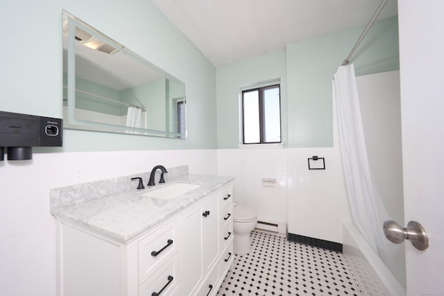 bathroom with baseboard heating, tile walls, water heater, toilet, and wainscoting