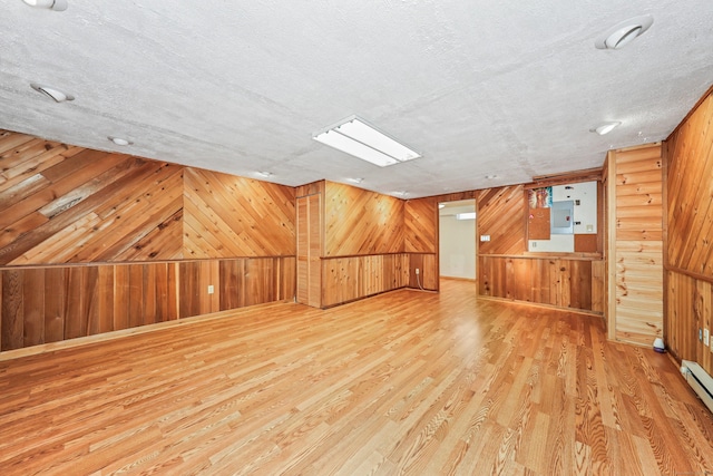 bonus room featuring wood walls, wood finished floors, electric panel, and a textured ceiling