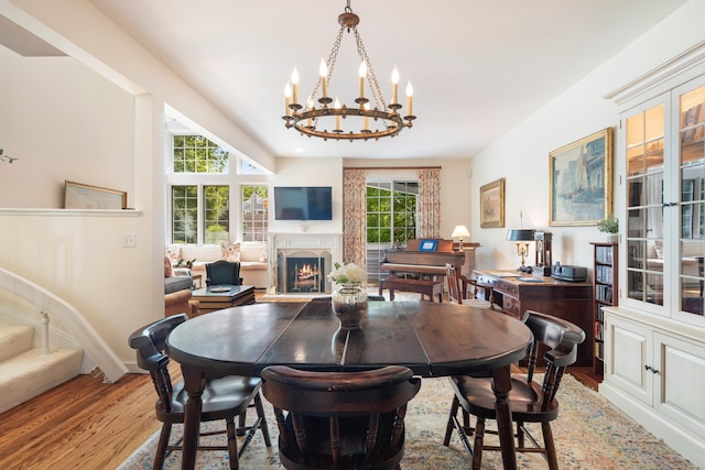 44 Hale Ln, Darien, CT 06820 - dining space featuring wood finished floors, a chandelier, a lit fireplace, and baseboards