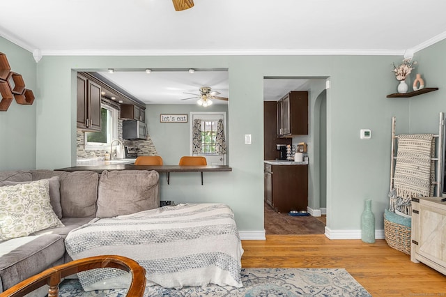 173 Columbia St, New Britain, CT 06052 - living area with light wood-style floors, ceiling fan, ornamental molding, baseboards, and arched walkways
