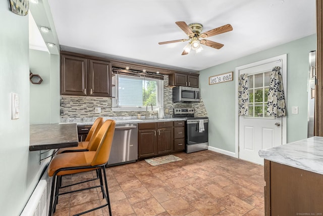 173 Columbia St, New Britain, CT 06052 - kitchen featuring appliances with stainless steel finishes, backsplash, dark brown cabinetry, ceiling fan, and a sink