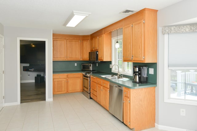 kitchen featuring stainless steel appliances, a sink, dark countertops, and baseboards