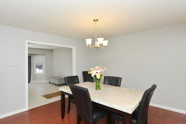 dining room with a chandelier, baseboards, and dark wood-style flooring