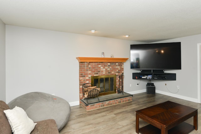 living area with wood finished floors, a brick fireplace, and baseboards