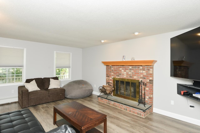 living room with wood finished floors, a fireplace, baseboards, and a textured ceiling